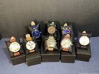 Wide shot showing all eight watches on display cushions