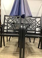 Front view of two aluminum arm chairs with lattice-back design and blue outdoor umbrella above and behind