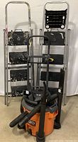 Full view of two aluminum step ladders, metal handcart, and RIDGID shop vacuum