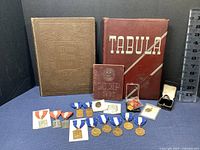 Vintage yearbooks from Massachusetts College of Pharmacy 1926, Whoo-Whoo 1928, Tabula 1945, and various medals and pins.