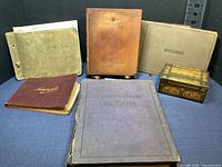 Six items displayed including three scrapbooks, one album, one drawing book, and a handcrafted box.