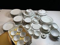 Photo showing the majority of plates, bowls, cups, and serving pieces laid out on a table