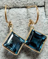 Close-up photo of the pair of earrings showing blue topaz square stones in 10K yellow gold setting.