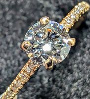 Close-up of center round diamond and pavé-set diamonds on yellow gold band