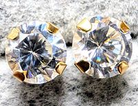 Close-up of two round clear cubic zirconia stones set in 14K yellow gold prong settings.