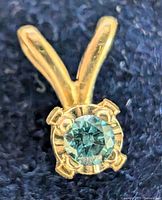 Close-up of the pendant showing the blue diamond and gold setting, highlighting the stone's cut and prongs.