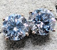 Close-up front view of both earrings showing round brilliant diamonds in 4-prong settings