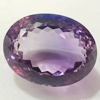 Close-up view of large faceted oval amethyst gemstone showing color and cut detail.