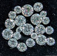 Cluster of loose round brilliant diamonds on black background