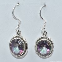 Front view of silver earrings with oval mystic topaz stones set in a detailed silver bezel with rope pattern, attached to silver hooks.