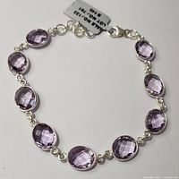 Silver bracelet displayed fully extended showing its linked pink amethyst stones and clasp.
