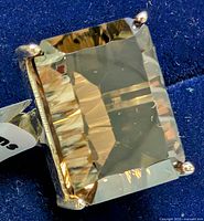 Close-up of the rectangular faceted smokey quartz gemstone in silver setting under good lighting.