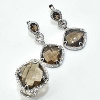 Pair of silver dangle earrings with pear and cushion faceted smokey quartz stones surrounded by small clear stones on white background.