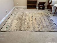 Top side view of rectangular beige area rug laid flat on floor showing overall pattern of horizontal stripes and geometric accents.