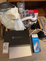 Box containing multiple bathroom related items including Shower Envy Technologies shower filter box, Aqua Theory replacement shower filters in white plastic packaging, and various small beauty and personal care items.