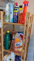 Wide view of wooden shelf with various spray bottles and cleaning products including Febreze, WD-40, Lysol, and others