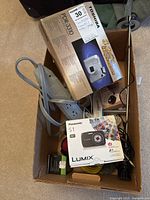 Box with Toshiba PDR-3310 digital camera and Panasonic Lumix S1 box showing included gadgets and power strip.