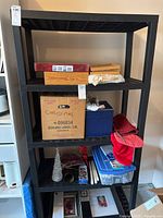 Full view of the black resin shelving unit with four shelves and assorted items on shelves (items not included).