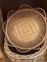 Round wicker basket with decorative scalloped edge and loop handles, showing detailed weave pattern