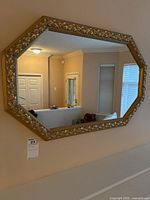 Front view of the large octagonal mirror hanging on a beige wall in a living room area.
