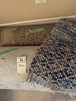 Three area rugs stacked with size measurements labeled on tape, including 32x66 and 32x90 inches