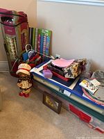 Full lot overview showing ceramic doll, gift bags, rolls of wrapping paper, framed art, and platters.