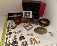 Photo showing assortment of costume jewelry items including necklaces, bracelets, brooches, earrings, decorative wooden box.