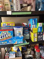 Wide view of various kitchen and laundry cleaning products on shelf showing brands and packaging.