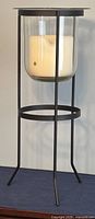 Side and angled views of the black metal candle holder with clear glass votive and white candle inside.