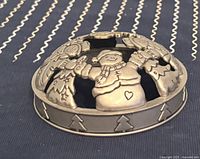 Close-up front view of pewter jar candle topper with snowman and Christmas tree cutouts