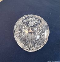 Crystal hollow orb decoration with intricate leaf and star cut patterns on a dark surface.