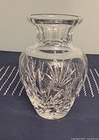 Large crystal vase with geometric cuts on a navy cloth with white stitching