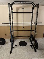 Full view of black power rack with chrome barbell, cable pulley loaded with weight plate and side-mounted plates