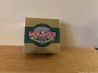 Gold colored limited edition Monopoly 60th Anniversary box on a wooden surface.