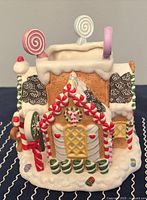 Front left view showing gingerbread house style with candy cane pillars and lollipop roof decorations