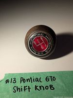Top view of the wooden shift knob showing the Pontiac Motor Division emblem in red and metal.