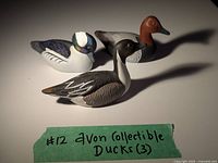 Three Avon collectible miniature duck figurines arranged together with green label showing '#12 Avon Collectible Ducks (3)'