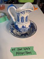 Small blue and white ceramic pitcher with floral decorations placed inside matching bowl.