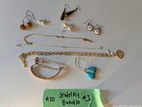 Photo showing all items: gold-tone necklace with pendant, two gold-tone bracelets, and six pairs of earrings in various styles and materials including brown tapered, pearl, turquoise, silver spiral, and amber bead earrings.