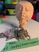 Front view of the carved wooden mask with metal base holding candle, incense holders and amethyst cluster.