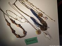 Full view of all 7 necklaces laid out showing variety of styles including wooden beads, chains, pendants, and tassels.