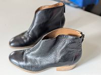 Pair of black leather ankle boots, side view showing low stacked heel and pointed toe.
