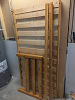 Single wooden bed frame components including headboard, footboard, and slats leaning against a wall.