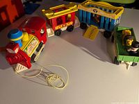 Overview of the Fisher-Price Circus Train toy set showing locomotive, two train cars, green wagon with animal, and minifigure
