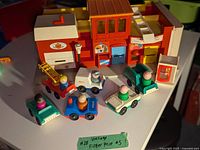 Overall view of the main red building with seven vehicles with attached figures arranged in front.