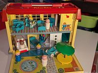 Front view of vintage Fisher-Price hospital playset with nursery and figures arranged inside and outside the building.