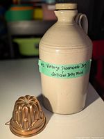 Photo of beige stoneware jug alongside copper jelly mold, showing size and items included