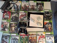 Photo of the full lot showing Xbox 360 console, two controllers, power adapter, and 17 Xbox 360 game cases including major franchises.