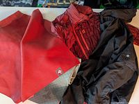 Two rolled-out yoga mats: one red Manduka Travelling mat and one basic red yoga mat, along with a red quilted jacket and black jacket.