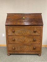 Front view of closed drop-front desk showing three drawers and lock